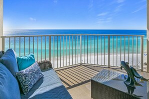 A balcony with a view of a beach, a sofa with patterned cushions, and a decorative sculpture. - Tides 1506 Oceanfront Penthouse. Million Dollar View! (Destin)