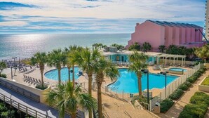 Ein Resort mit großem Pool, Palmen und Blick auf den Ozean.