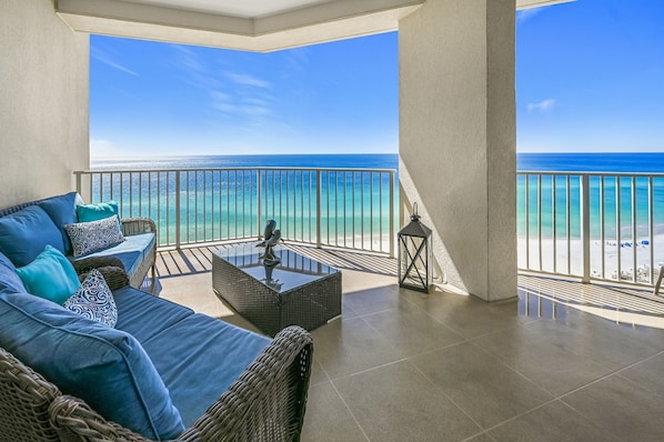 A balcony with a view of the ocean, furnished with a sofa and a table.