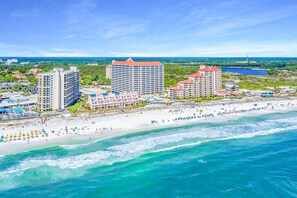 Un hotel frente al mar con varias construcciones, una playa y vistas al océano.
