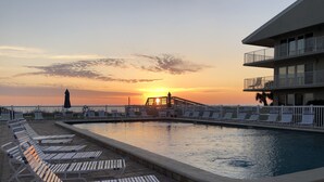 Un área de piscina con sillones de descanso y vistas al atardecer.