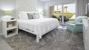 Un dormitorio con cama, mesitas de noche, una silla y vistas al exterior.
