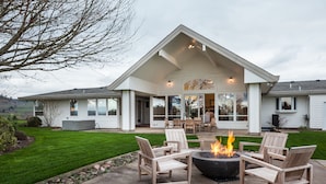 A house with a covered patio, outdoor seating, and a fire pit.