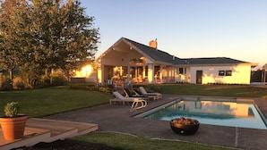 A modern house with a pool, outdoor seating, and a well-maintained lawn.