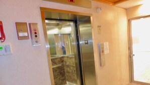 An elevator with a metallic finish, a control panel with buttons, and a wall-mounted emergency phone. - Beach Front Studio With Spectacular Ocean Views (Honolulu)