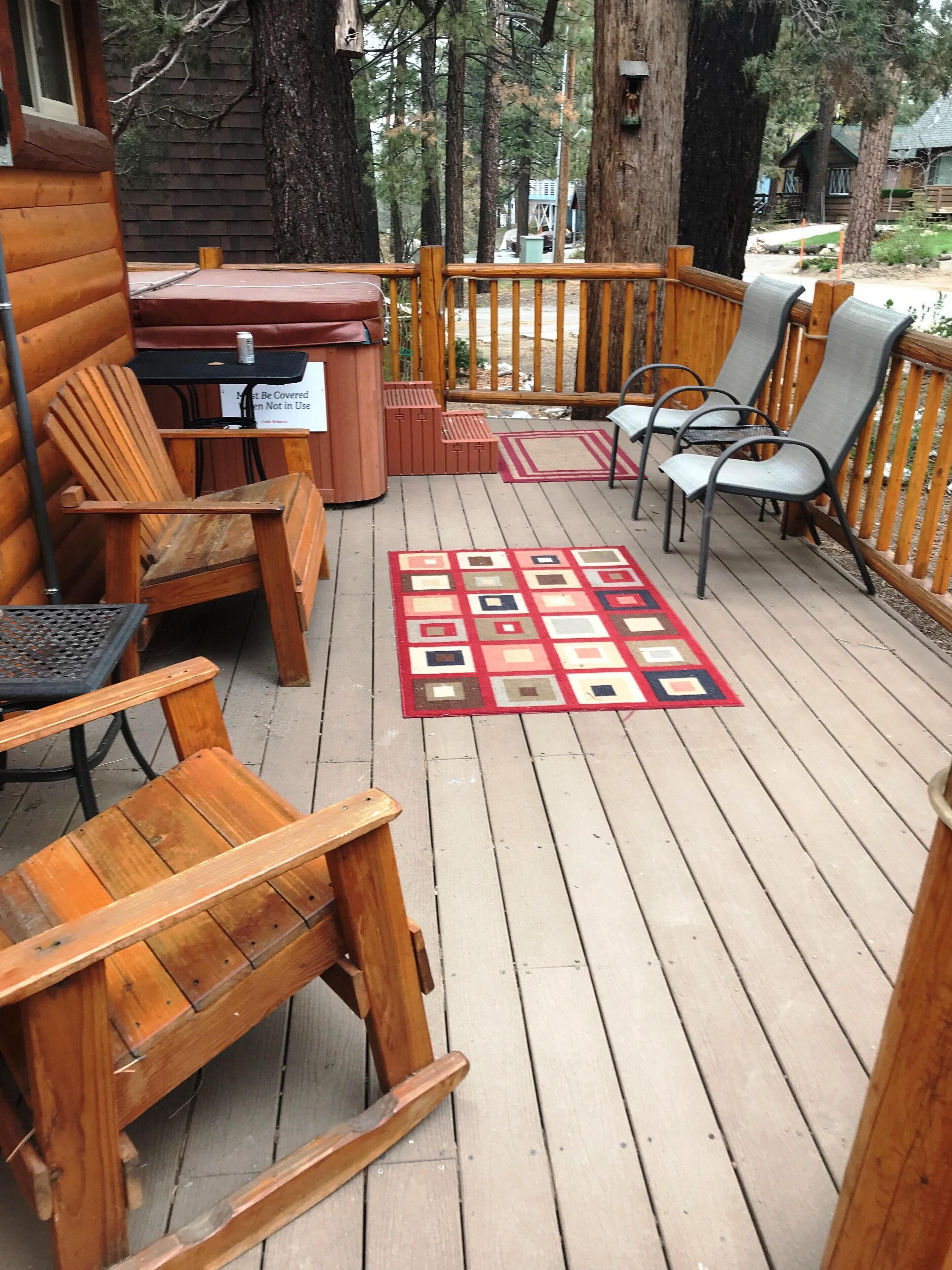 A wooden deck with outdoor seating, including chairs and a table, surrounded by a wooden fence.
