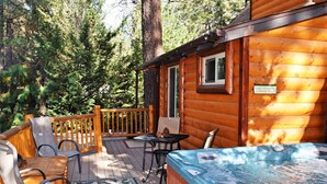 Une cabane en bois dotée d’un bain à remous, d’un espace extérieur aménagé et offrant une vue sur une forêt dense.