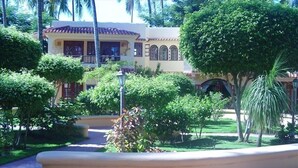 A building with a tiled roof and arched windows, surrounded by lush greenery and palm trees. - 5 Star Rated, Beautiful Beach Best Value at Bavaro Beach! No Extra Fees (Punta Cana)