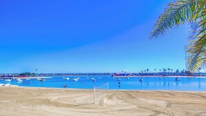Ein Strand mit klarem, blauem Wasser, Booten und einer Sandfläche.