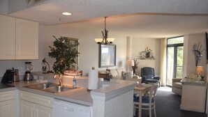 Una cocina moderna con una isla central, lavavajillas integrado y un comedor con una silla y una mesa.