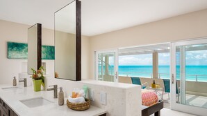A modern bathroom with a large mirror, two sinks, and a view of the ocean through a sliding glass door. - Villa Blue Heaven-Just Steps to  Beach and Turquoise Water -  Best Sunsets!  (Providenciales)