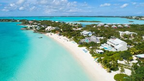 An aerial view of a coastal resort with a sandy beach, clear turquoise waters, and several overwater bungalows. - Villa Blue Heaven-Just Steps to  Beach and Turquoise Water -  Best Sunsets!  (Providenciales)