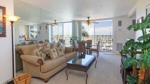 A spacious living room with a large window, a sofa, a coffee table, and a dining area.