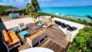A wooden deck with outdoor seating, a hot tub, and a view of the ocean.