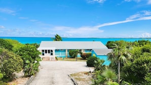 A two-story house with a porch, a swimming pool, and a view of the ocean.
