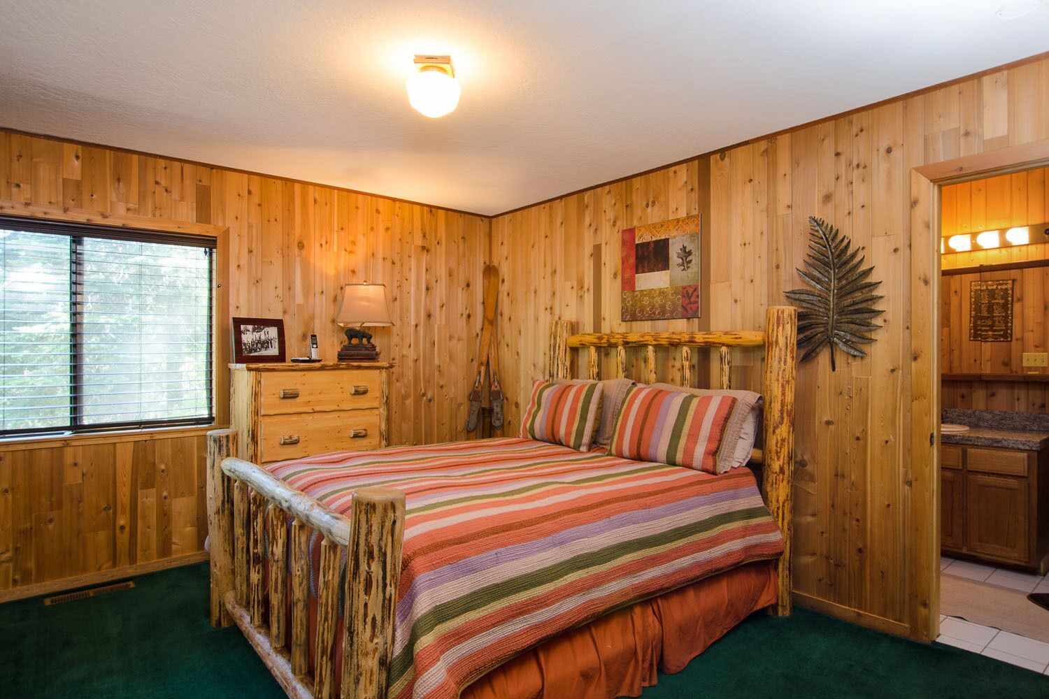 Un dormitorio con paneles de madera, una cama, un tocador y una ventana.