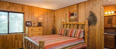 Un dormitorio con paneles de madera, una cama, un tocador y una ventana.