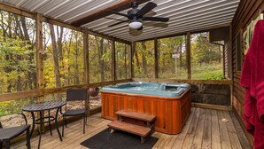 A wooden deck with a hot tub, a ceiling fan, and a table with chairs. - Charming 3BR / 3BA With Hot Tub, Fireplace & Pool Table (Galena)