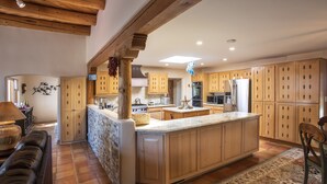 Una cocina amplia con armarios de madera, una isla grande y un protector de salpicaduras de piedra.