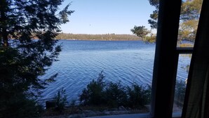 A room with a large window overlooking a lake, surrounded by trees. - Secluded 2 acre Lakeside Home, boat & motor included on 5 lake chain. free Wi-Fi (Eagle River)