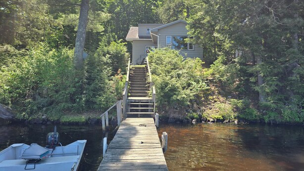 A wooden dock leading to a house surrounded by dense forest. - Secluded 2 acre Lakeside Home, boat & motor included on 5 lake chain. free Wi-Fi (Eagle River)