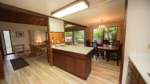 Una cocina amplia con armarios de madera, una isla central y un comedor con sillas y mesa de madera.