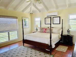 A four-poster bed with a white bedspread, a wooden headboard, and a nightstand with a lamp.