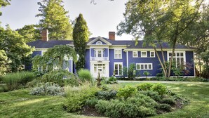 Une grande maison à deux étages, avec un jardin bien entretenu à l’avant.