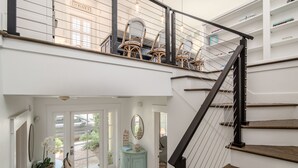 A staircase with a black handrail leading to a second-floor balcony with wicker chairs. - Luxe gulf side living between Rosemary & Alys - walk to beach & oceanfront pool  (Panama City Beach)