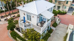 A two-story house with a balcony, a covered porch, and a small garden area. - Luxe gulf side living between Rosemary & Alys - walk to beach & oceanfront pool  (Panama City Beach)