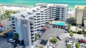 Et hotel med flere etager, en swimmingpool, parkeringsplads og udsigt over havet.