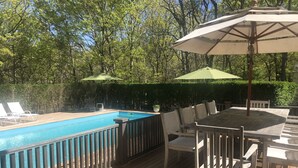A wooden deck with a swimming pool, outdoor furniture, and umbrellas.