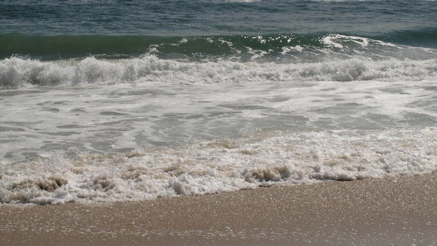 A beach with waves approaching the shore.