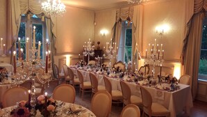 Une salle à manger élégante, avec une longue table dressée pour le repas, entourée de chaises.