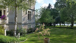 Un bâtiment historique doté d’un jardin bien entretenu, d’une statue et offrant une vue sur un lac.