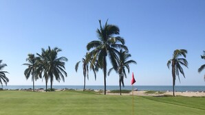 A well-maintained golf course with a clear view of the ocean and palm trees in the background. - 2 BR condo nestled between Pacific Ocean beach and golf course    (Mazatlan)