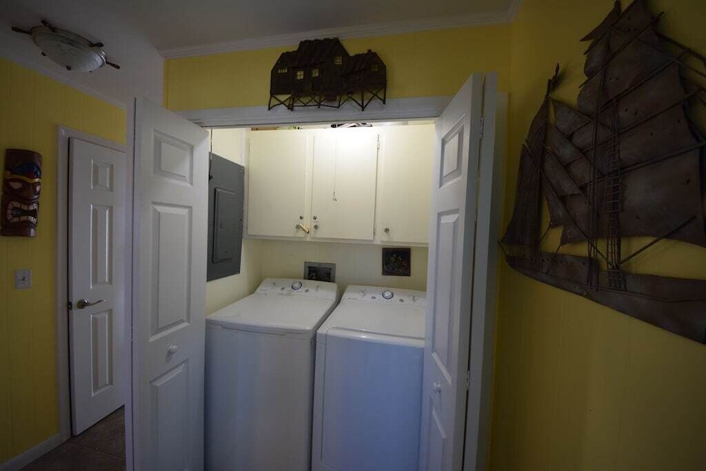 A laundry room with two stacked washers and dryers, a small cabinet, and a decorative metal piece on the wall.