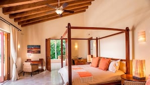 A four-poster bed with a wooden frame, a desk with a lamp, and a wicker chair. - Luxury Villa, Panoramic Views, Infinity Pool & Concierge (Punta Mita)