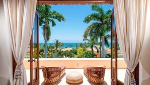 A balcony with wicker furniture and a view of the ocean and palm trees. - Luxury Villa, Panoramic Views, Infinity Pool & Concierge (Punta Mita)