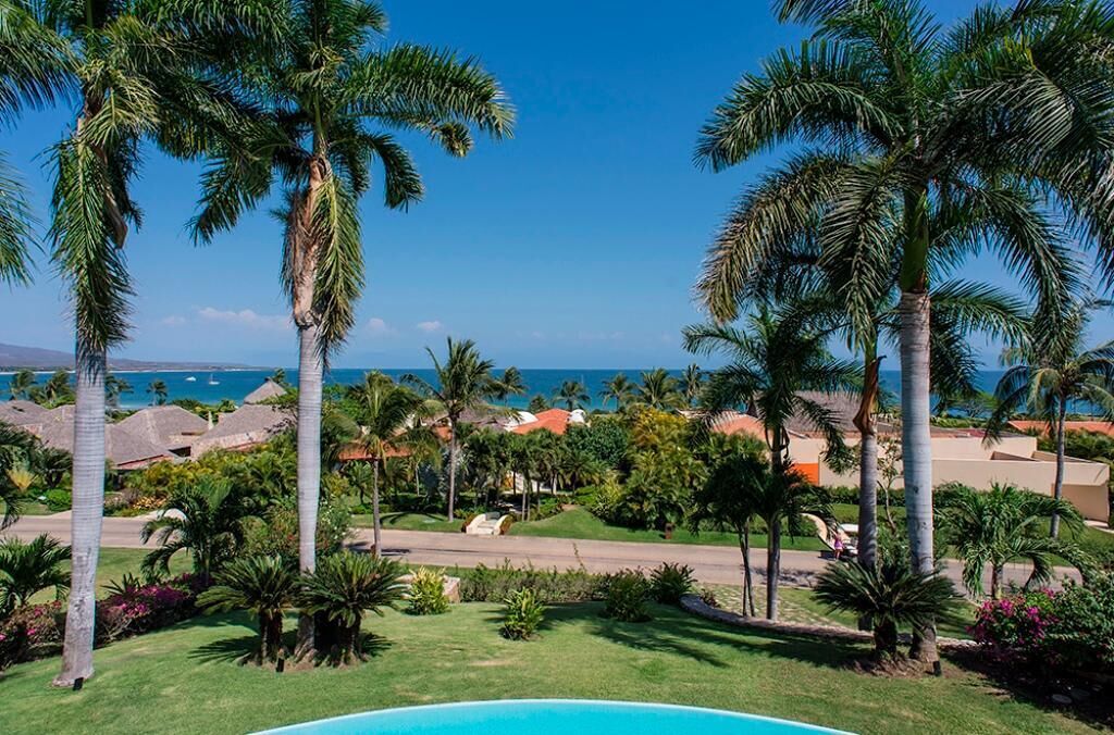 Un resort con piscina, palmeras y vista al océano.