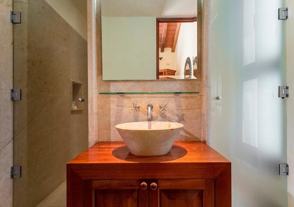 Une salle de bain avec un grand lavabo de forme ovale, un meuble-lavabo en bois et un miroir au-dessus du lavabo.