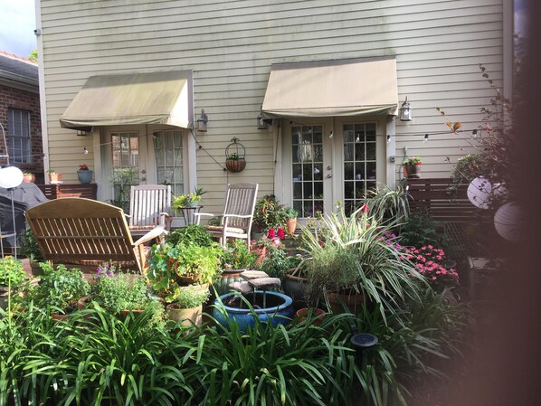 A patio with two chairs, a table, and various potted plants.