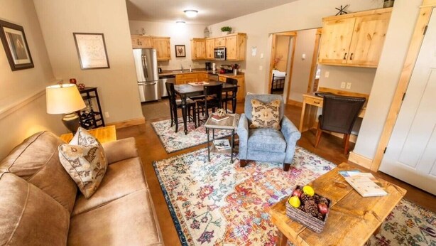 Una sala de estar con un sofá, una mesa de centro con frutas, una silla y una alfombra.