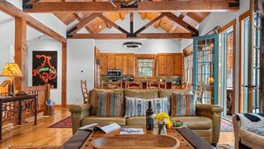 Ein geräumiges Wohnzimmer mit Ledersofa, Couchtisch aus Holz und einer Küche im Hintergrund.