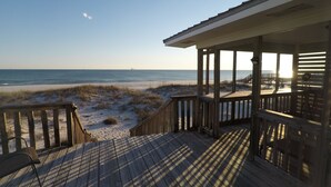 A wooden deck with a view of the beach and ocean.