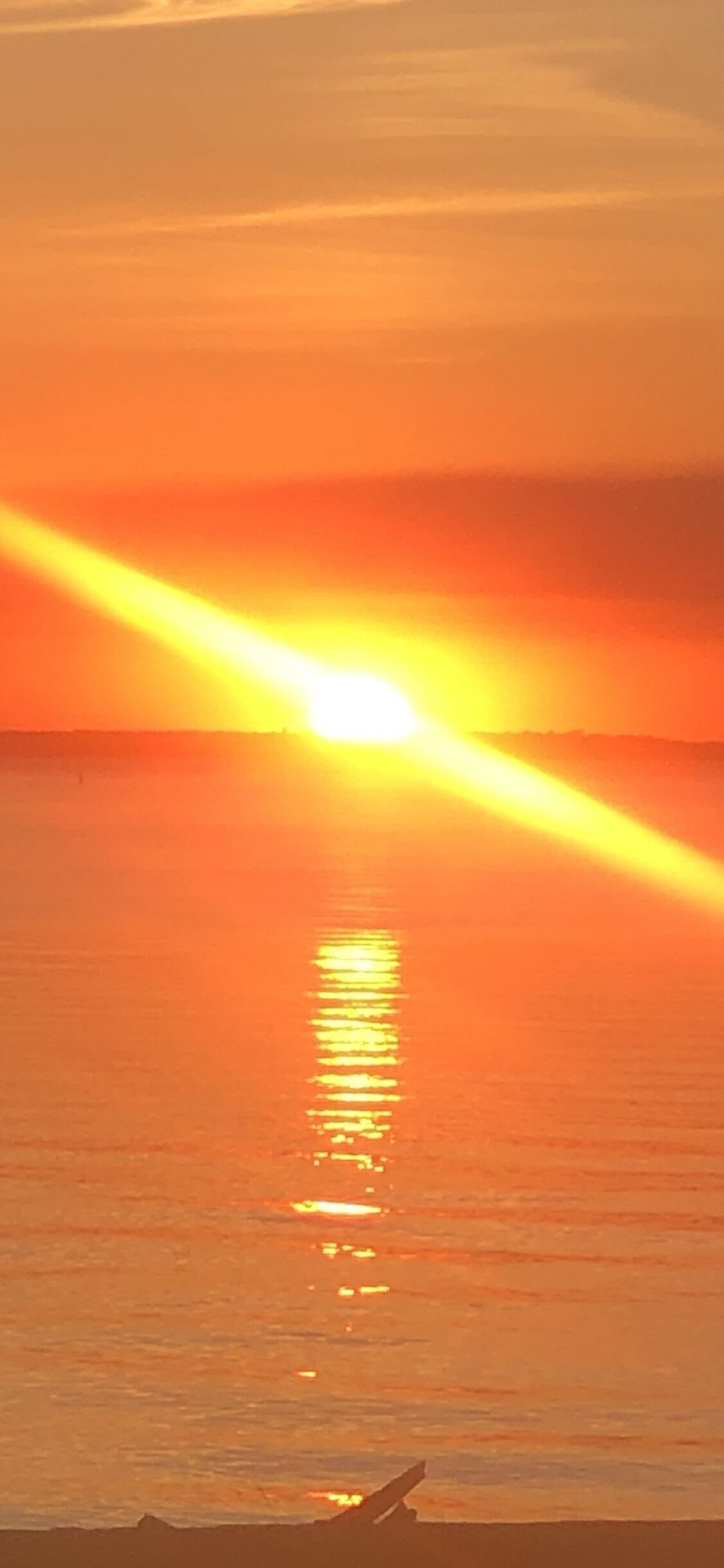 Un atardecer sobre un cuerpo de agua tranquilo, con un horizonte despejado.