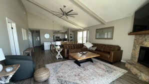 A spacious living room with a brown leather sofa, a wooden coffee table, and a patterned rug.