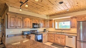 A spacious kitchen with wooden cabinets, granite countertops, stainless steel appliances, and a large island. - House - Southern Hills Serene Getaway (Hot Springs)