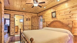 A wooden-paneled bedroom with a large bed, a ceiling fan, and a wooden wardrobe. - House - Southern Hills Serene Getaway (Hot Springs)