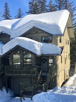 A two-story lodge with a stone facade, a balcony, and a snow-covered roof. - BEST LOCATION ON THE MOUNTAIN! Thunder Ridge 3 BR Ski in/Out Condo. Sleeps 8. (Fernie)